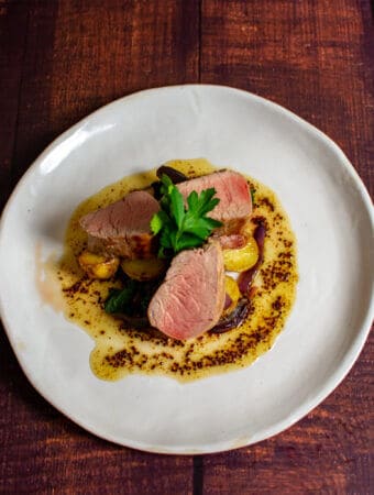 pork tenderloin, vegetables & honey mustard sauce on a white plate