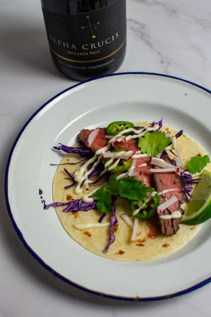 steak taco carne asada style on a plate with a chalk hill alpha crucis grenache wine in backgroundte