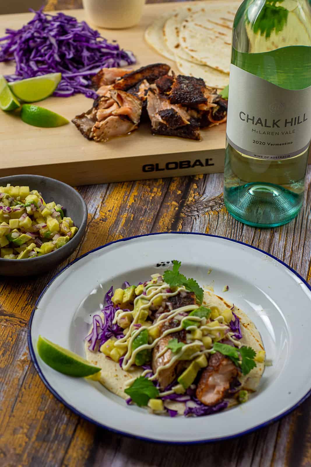 blackened salmon taco on a plate with chalk hill vermentino in background