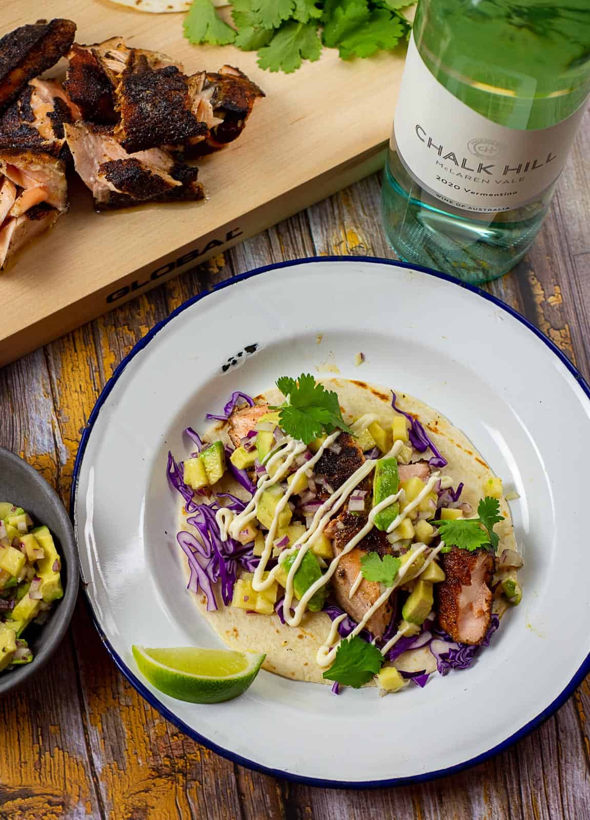 blackened salmon taco on a plate with chalk hill vermentino in background