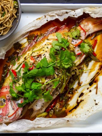 Cooked fish en papillote with bowl of noodles