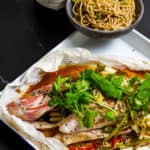 Cooked fish en papillote with bowl of noodles