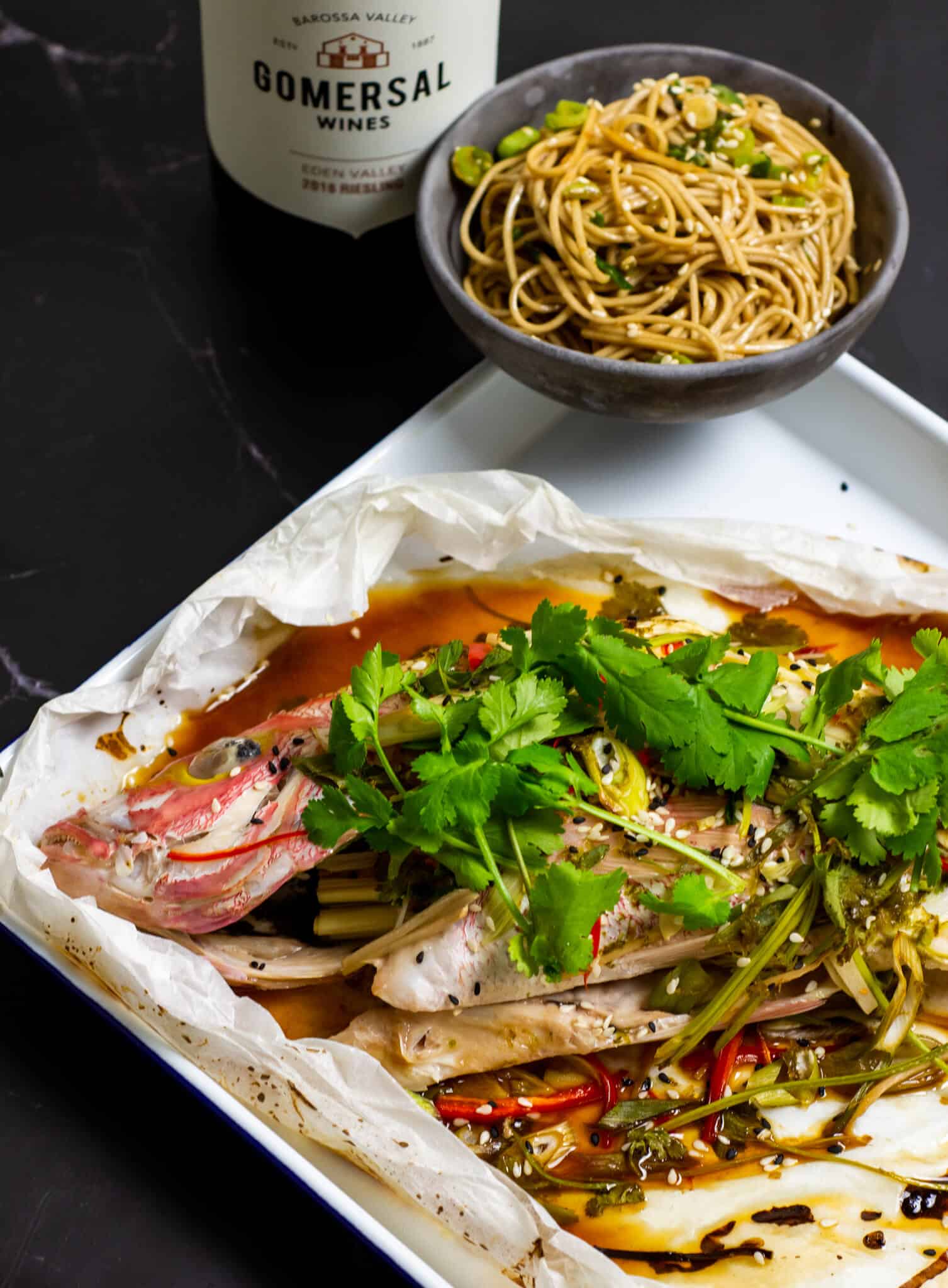 Cooked fish en papillote with bowl of noodles