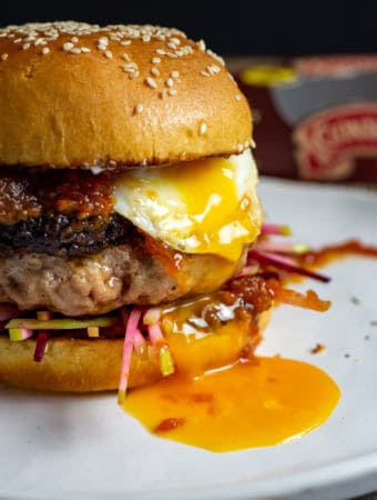 Close up of pork & black pudding burger with runny egg yolk. Clonakilty black pudding packet in background