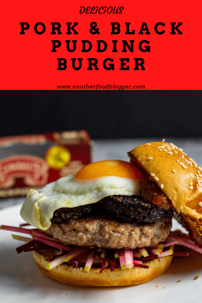 Pork & black pudding burger on a white plate with top bun off. Clonakilty pudding packet in background