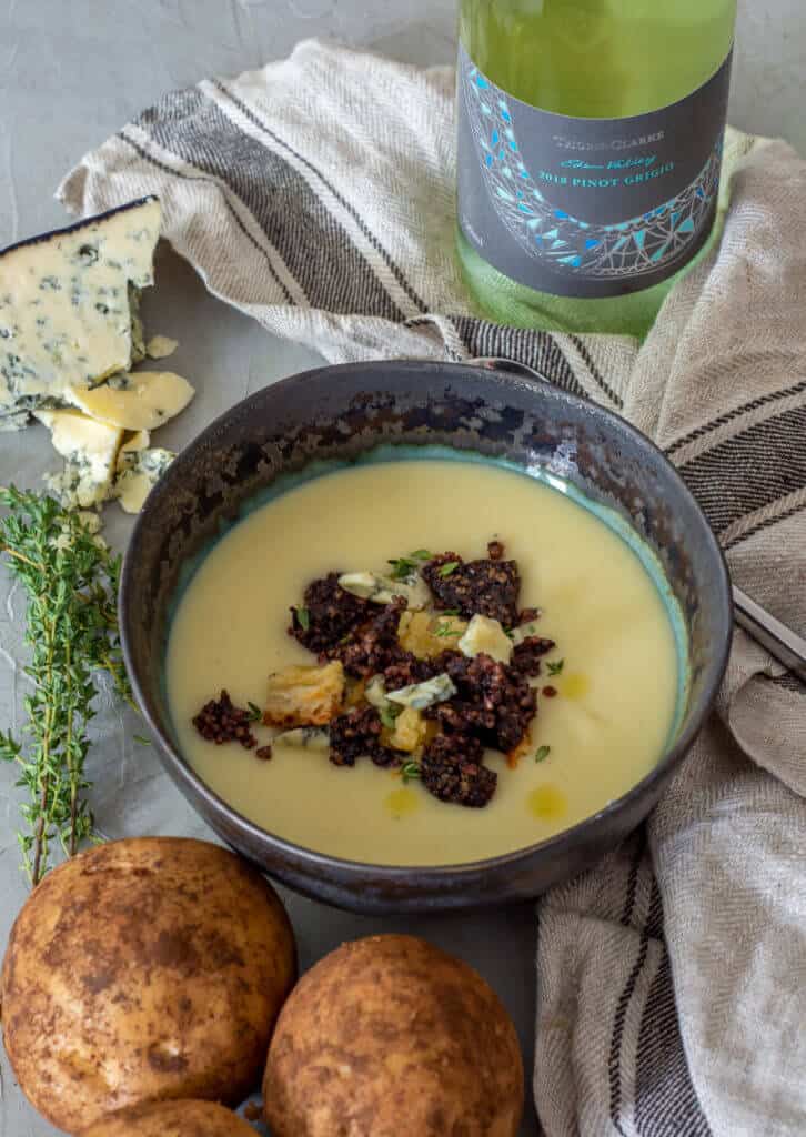Potato & leek soup in a bowl with a bottle of pinot grigio beside