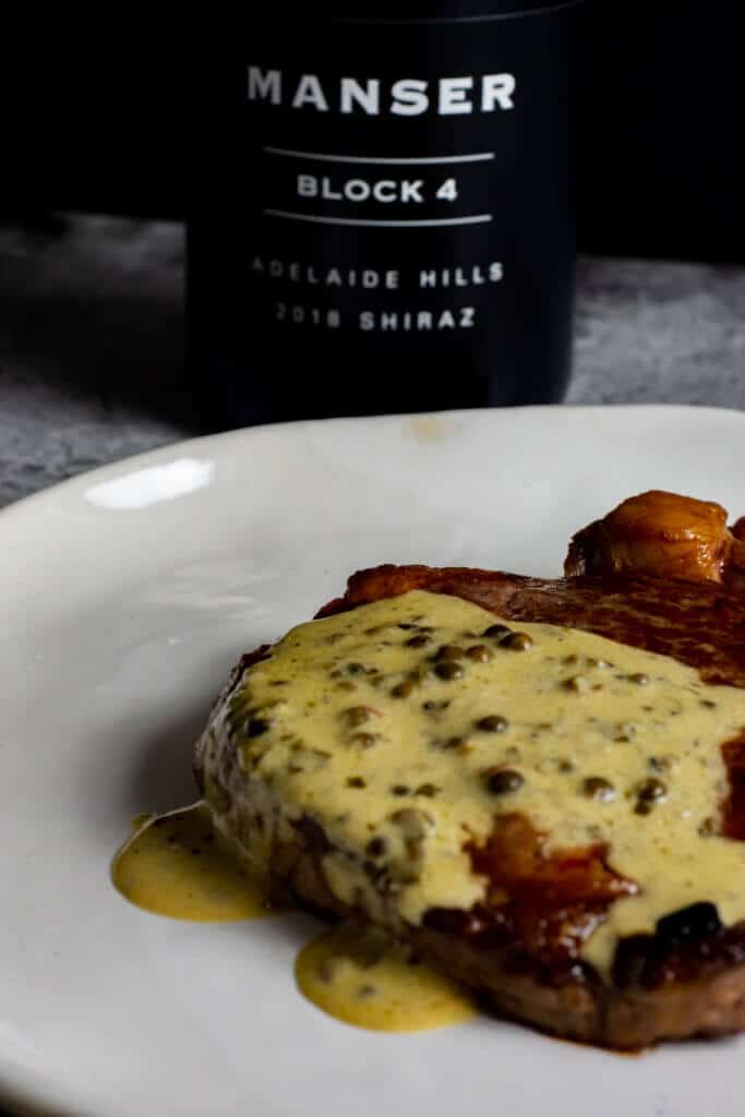 steak, peppercorn sauce on a plate with manser red wine