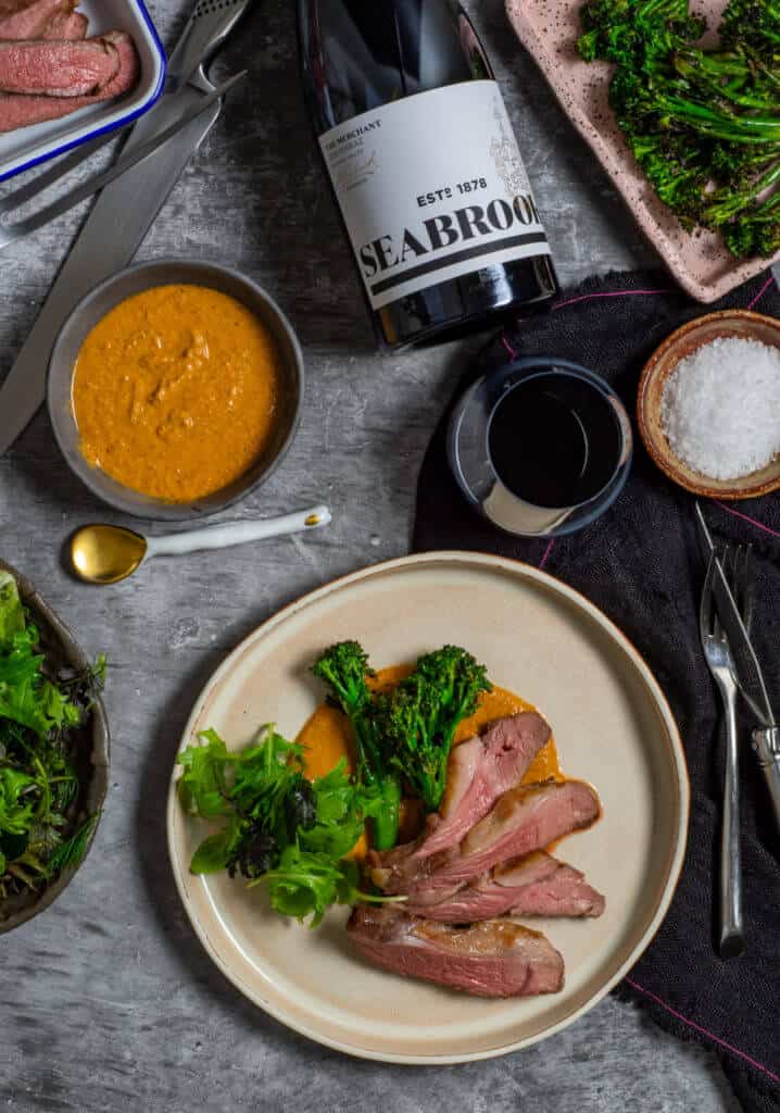 Seabrook wine shiraz, BBQ lamb, romesco sauce & charred broccolini on a table