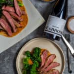 Seabrook wine shiraz, BBQ lamb, romesco sauce & charred broccolini on a table