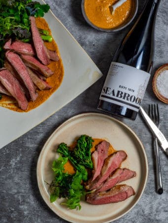 Seabrook wine shiraz, BBQ lamb, romesco sauce & charred broccolini on a table