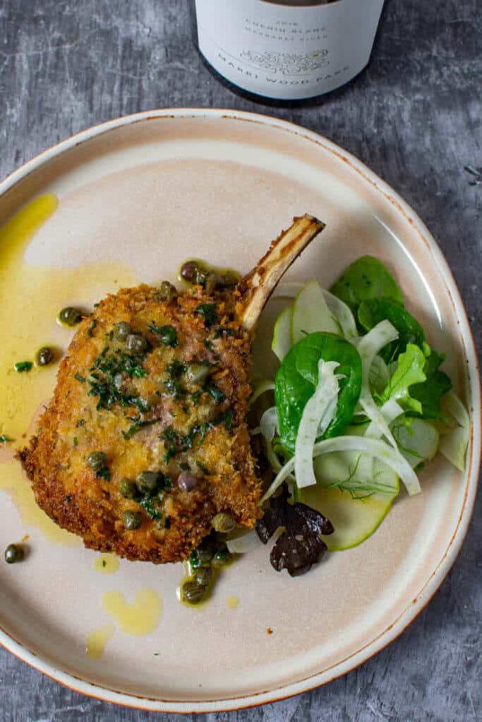 cooked veal cutlet, salad & sauce on a plate