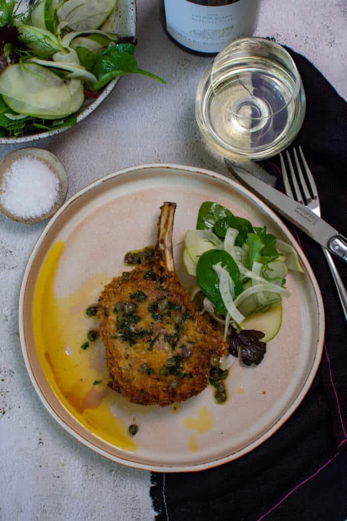 glass of wine, salad, cutelery, napkin & plate with crumbed veal cutlet