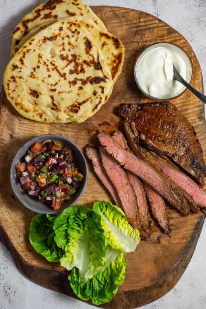 homemade pita bread, skirt steak, lettuce & salsa on wooden board