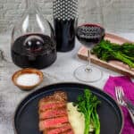 steak & onion soubise on a plate, decanter, glass of wine and bottle heirloom shiraz