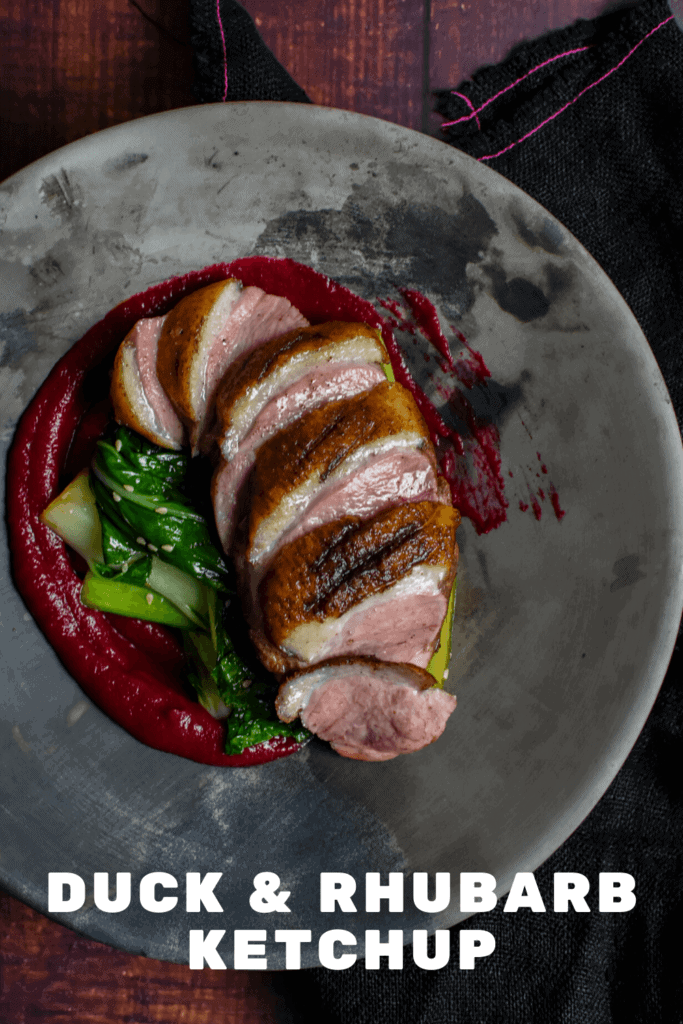 Duck breast, rhubarb ketchup & asian greens in a made of australia bowl on a table
