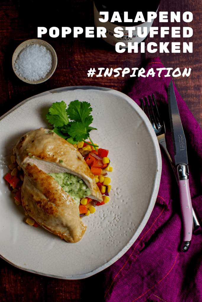 jalapeno popper stuffed chicken & corn hash on a plate, pink napkin, laguiole steak knife and bottle of gomersal wine