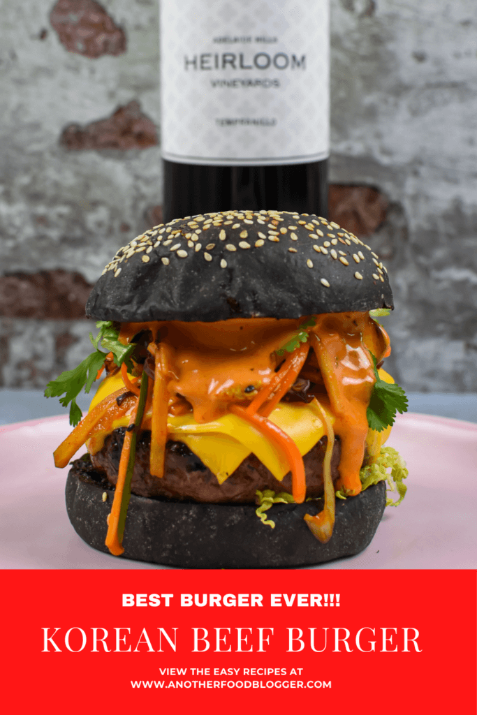 korean beef burger on a pink plate, heirloom tempranillo red wine behind it