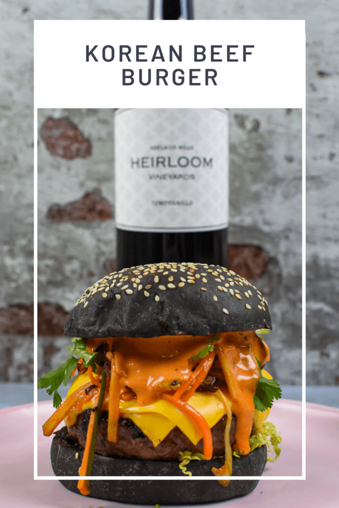 korean beef burger on a pink plate, heirloom tempranillo red wine behind it