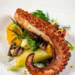 Grilled octopus salad on a white plate