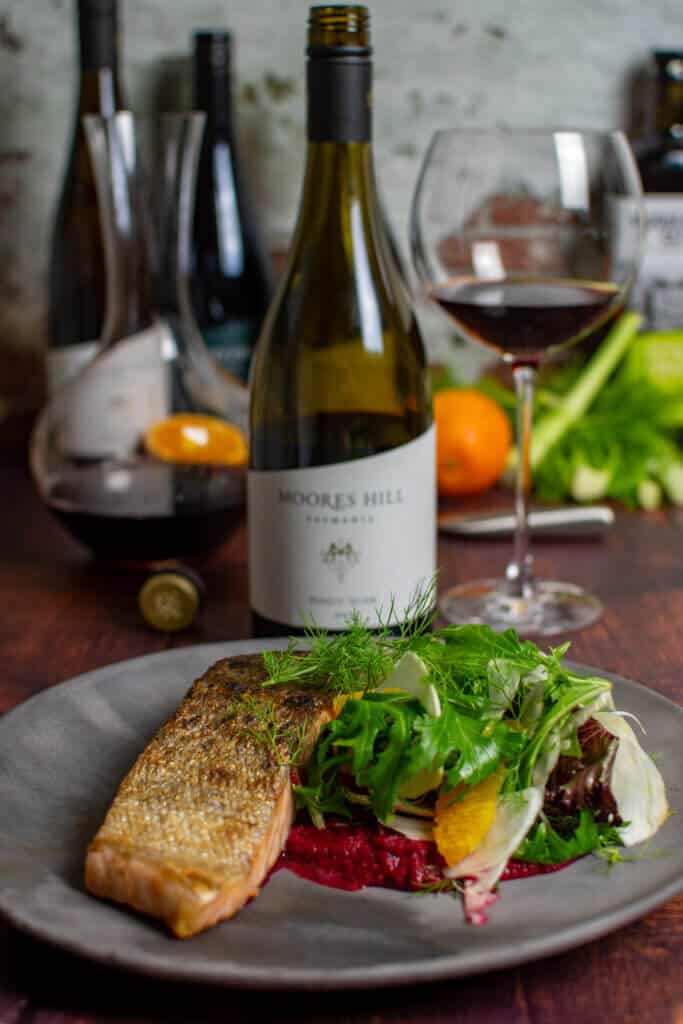 grilled salmon, beetroot hummus & fennel salad on a made of australia plate and a moores hill pinot noir in background