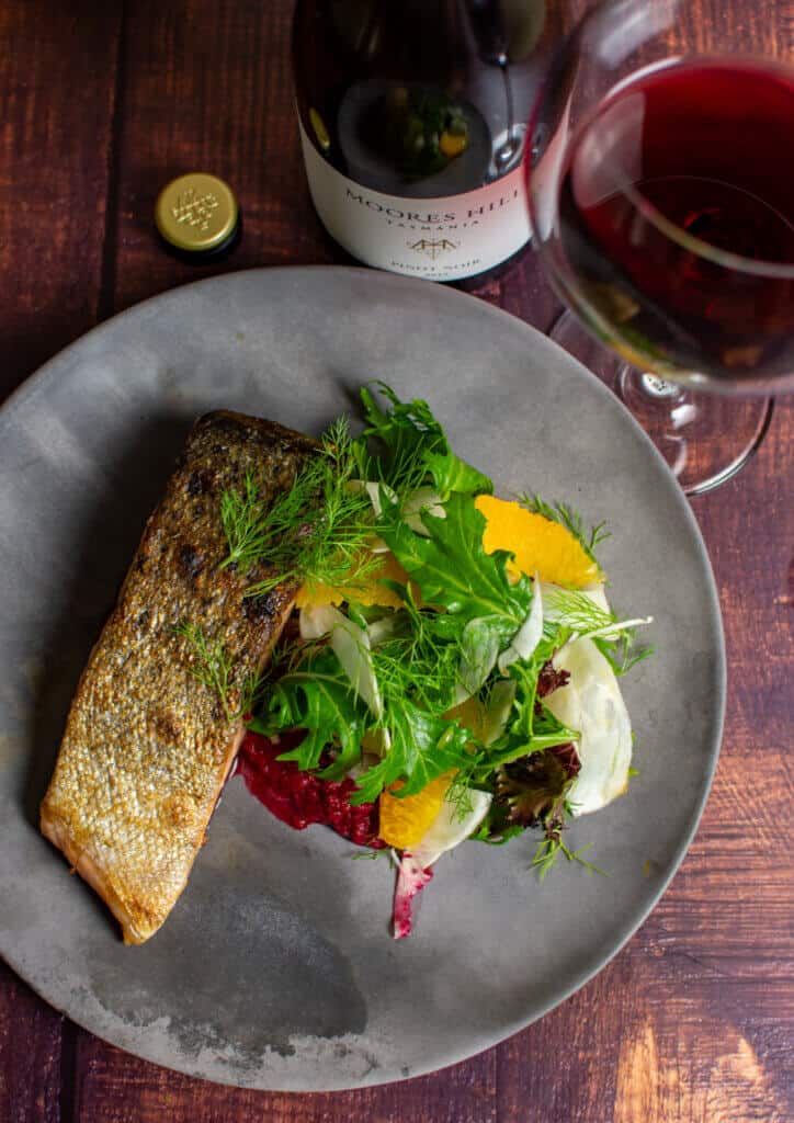 grilled salmon, beetroot hummus & fennel salad on a made of australia plate and a moores hill pinot noir