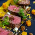 lamb, smoked squash puree, & pistachio dukkah on a black plate