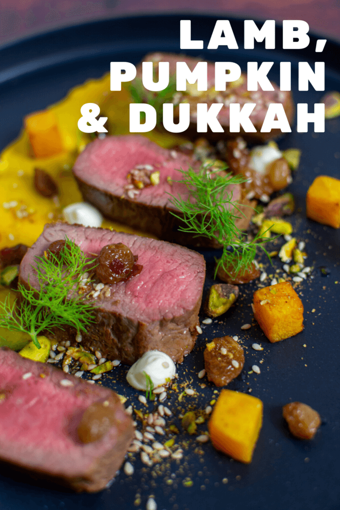 lamb, smoked squash puree, & pistachio dukkah on a black plate