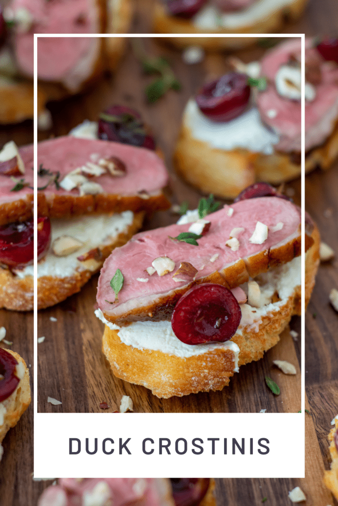 duck crostinis with cherries & goat cheese on wooden chopping board