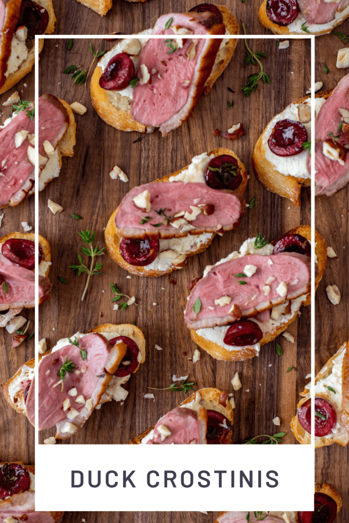 duck crostinis with cherries & goat cheese on wooden chopping board