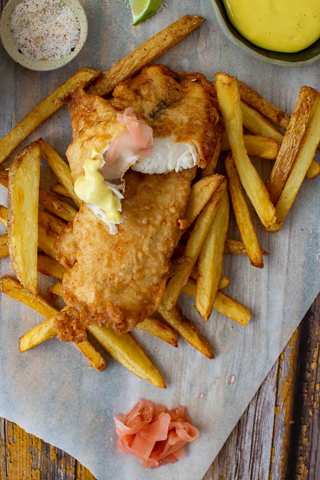 battered fish & chips & pickled ginger on a wooden table
