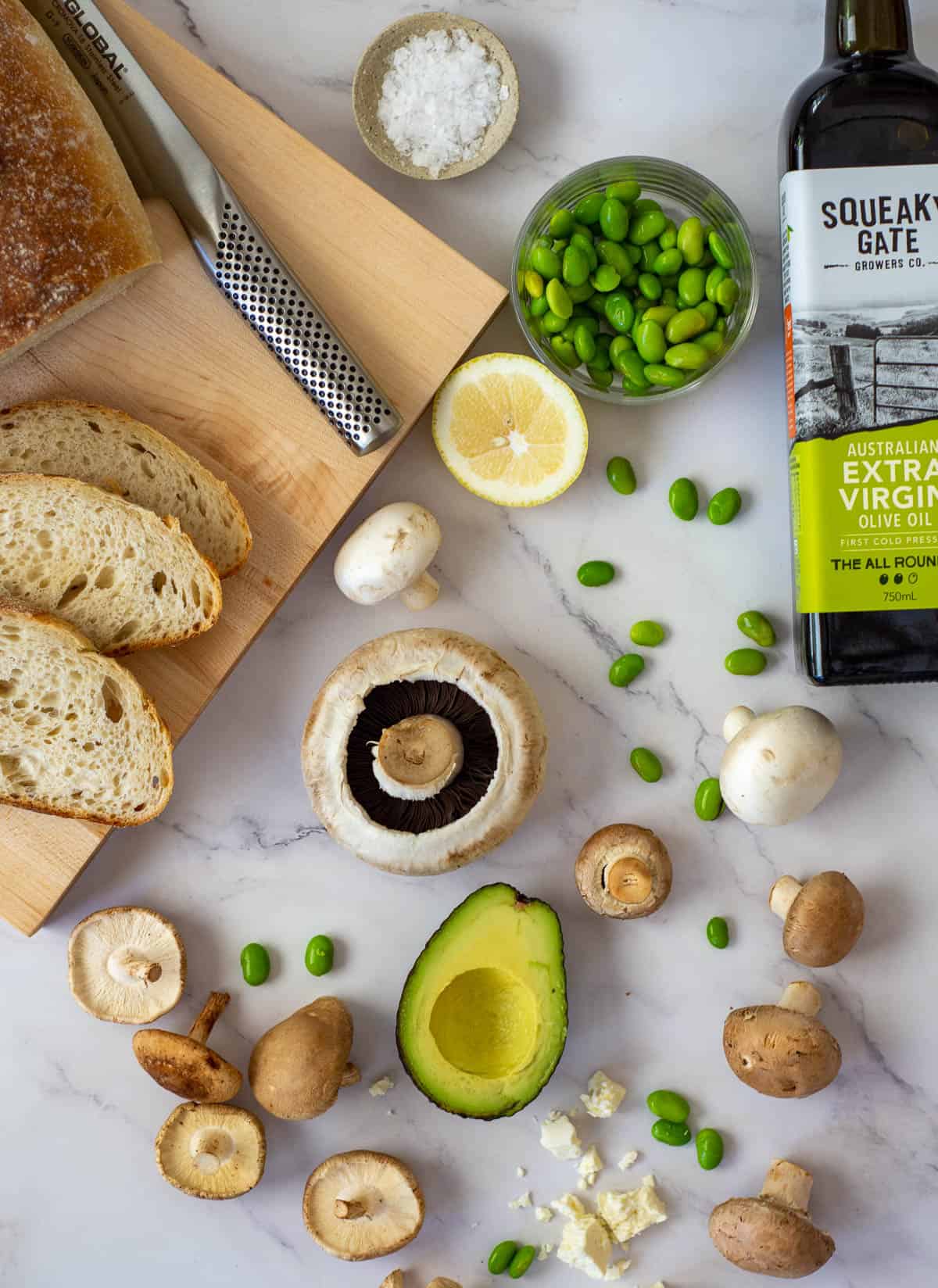 ingredients for mushroom avocado toast on countertop with squeaky gate olive oil