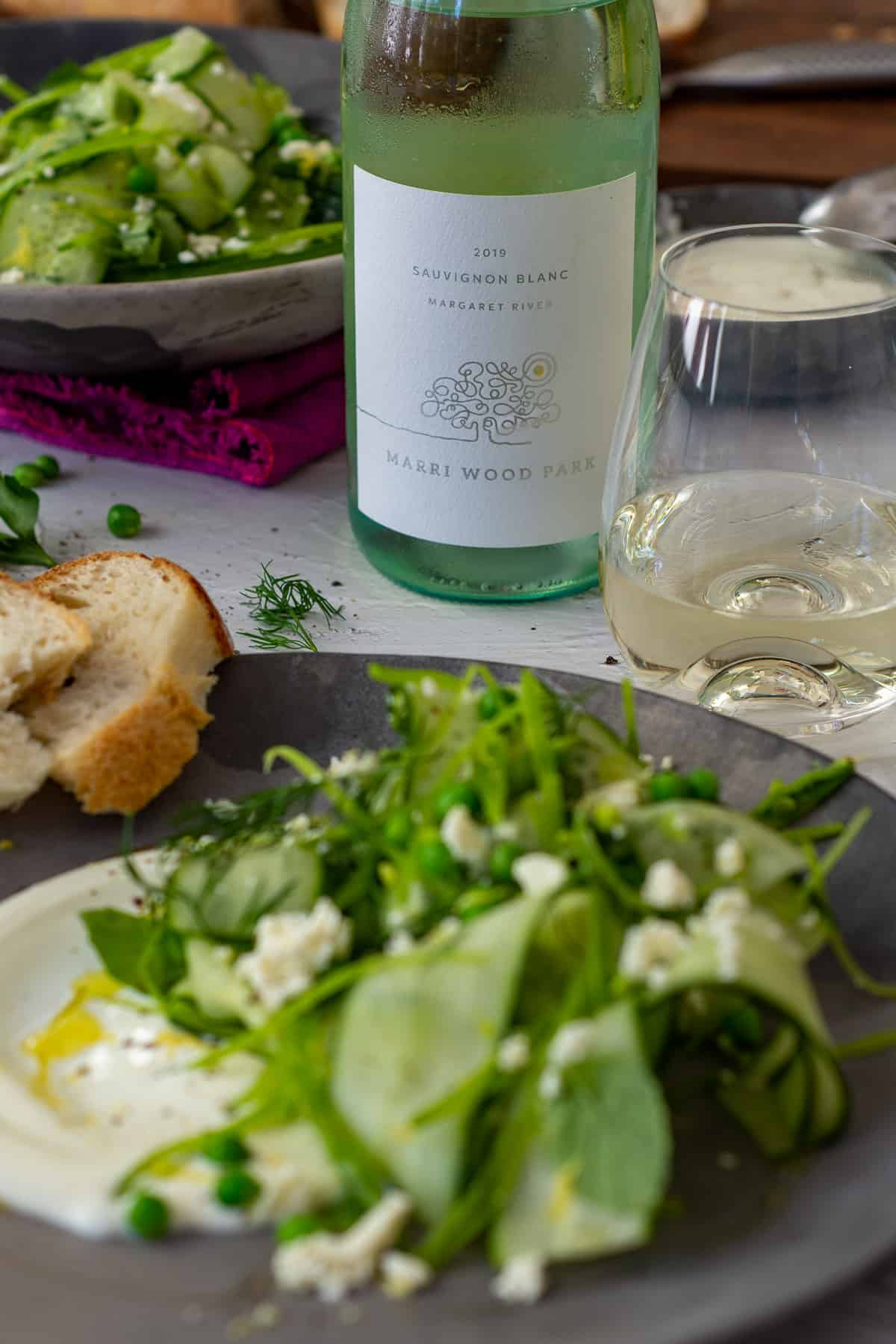 English pea salad on a plate, sourdough bread & Marri wood park sauvignon blanc