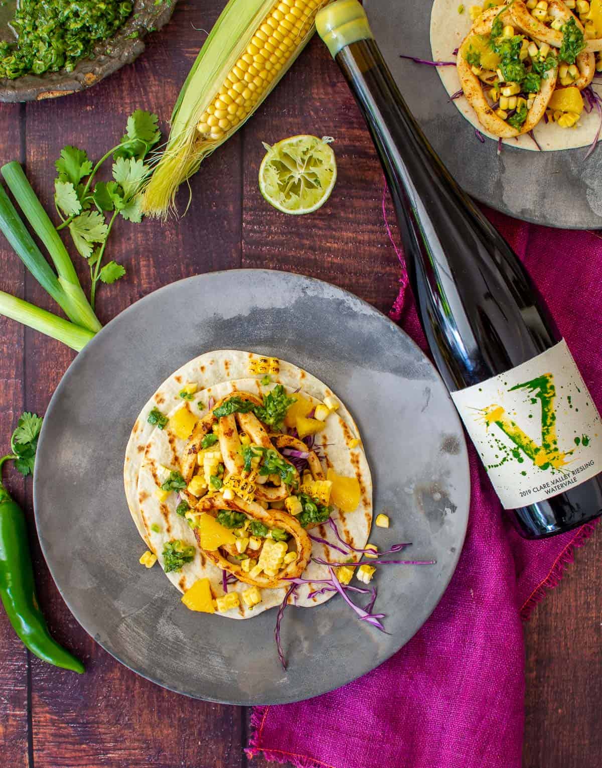 calamari tacos on a made of australia plate, vanguardist riesling & vegetables on a wooden table