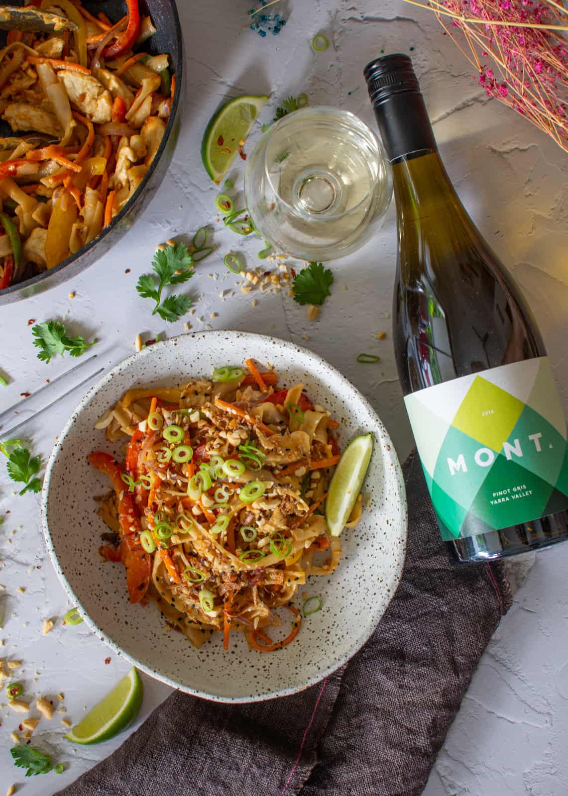 peanut butter chicken strifry in a bowl with mont pinot gris lying next to it