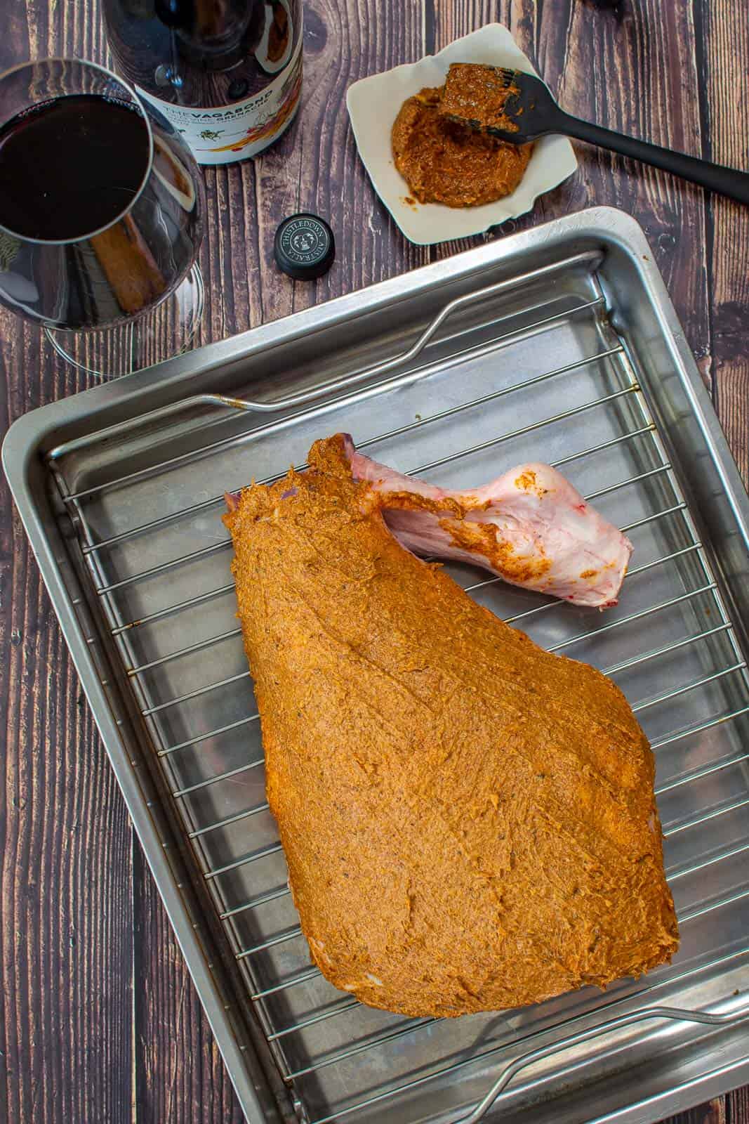 moroccan spiced butter rubbed lamb leg in a roasting tray with a bottle of thistledown vagabond grenache