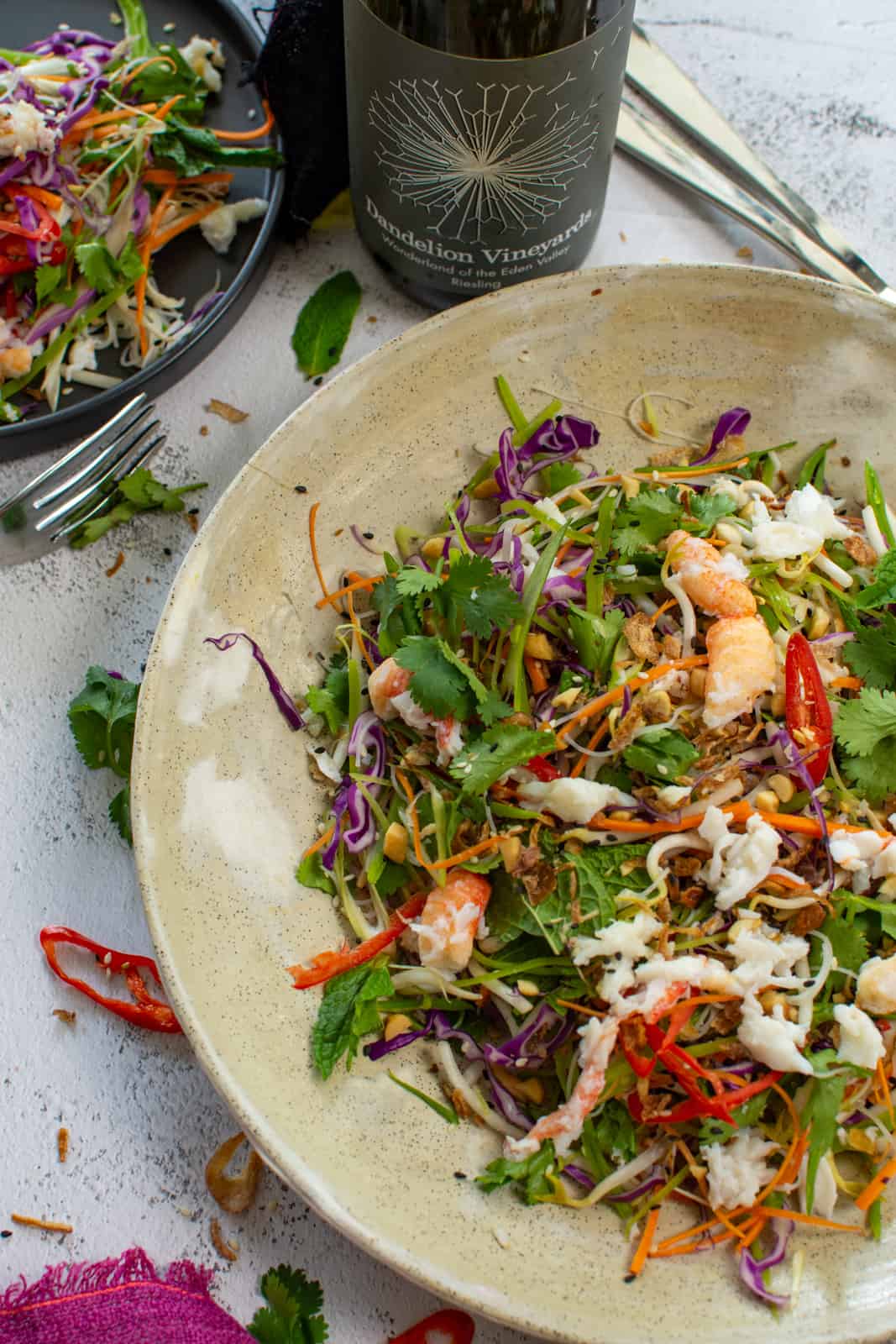 spicy crab salad in a bowl with bottle of dandelion riesling next to it 