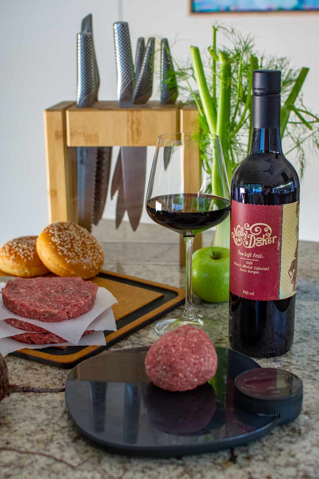 beef mince on a weighing scles with beef burger patties and a bottle of mollydooker wine behind it