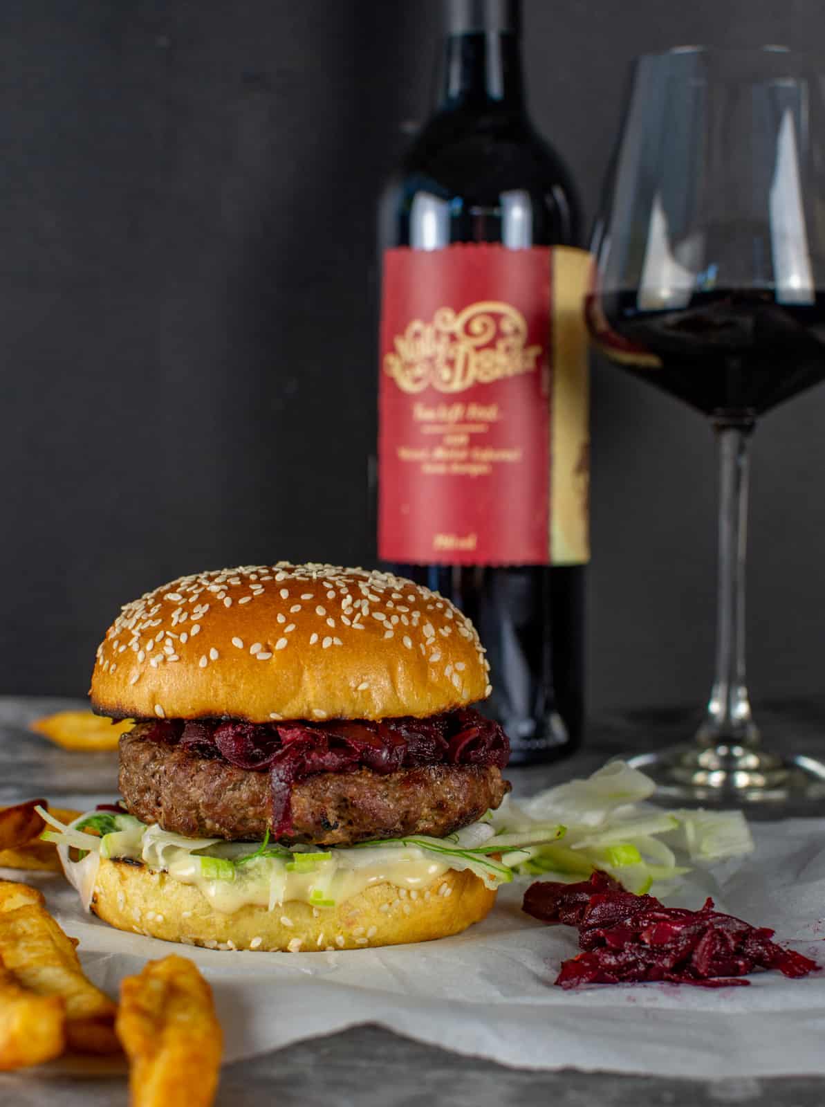 beef burger on parchmant paper with mollydooke wine behind it