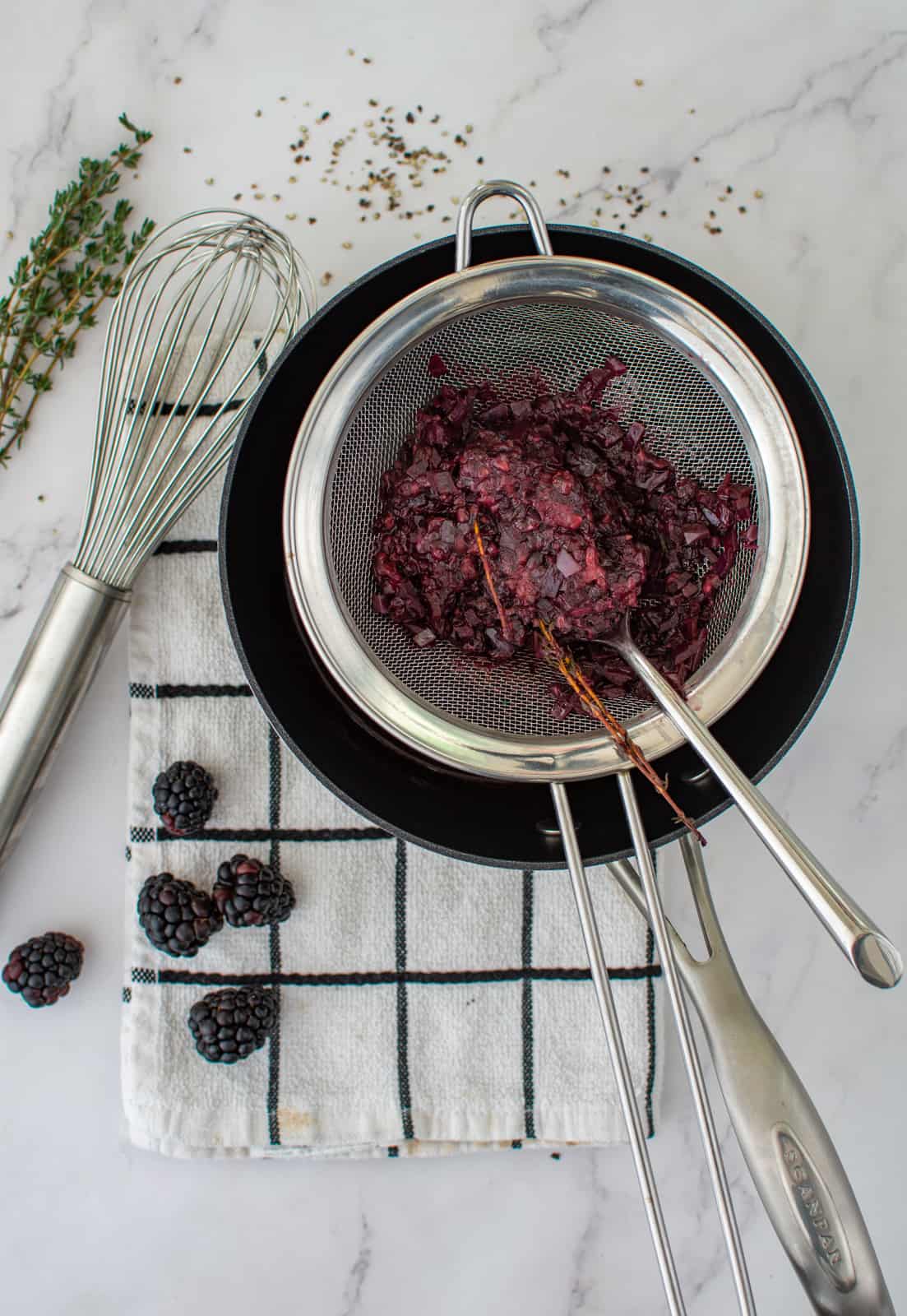 blackberry jus being strained into saucepan