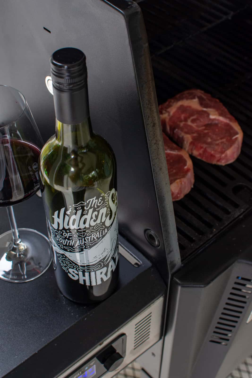 hidden sea shiraz next to BBQ with a couple scotch steaks cooking