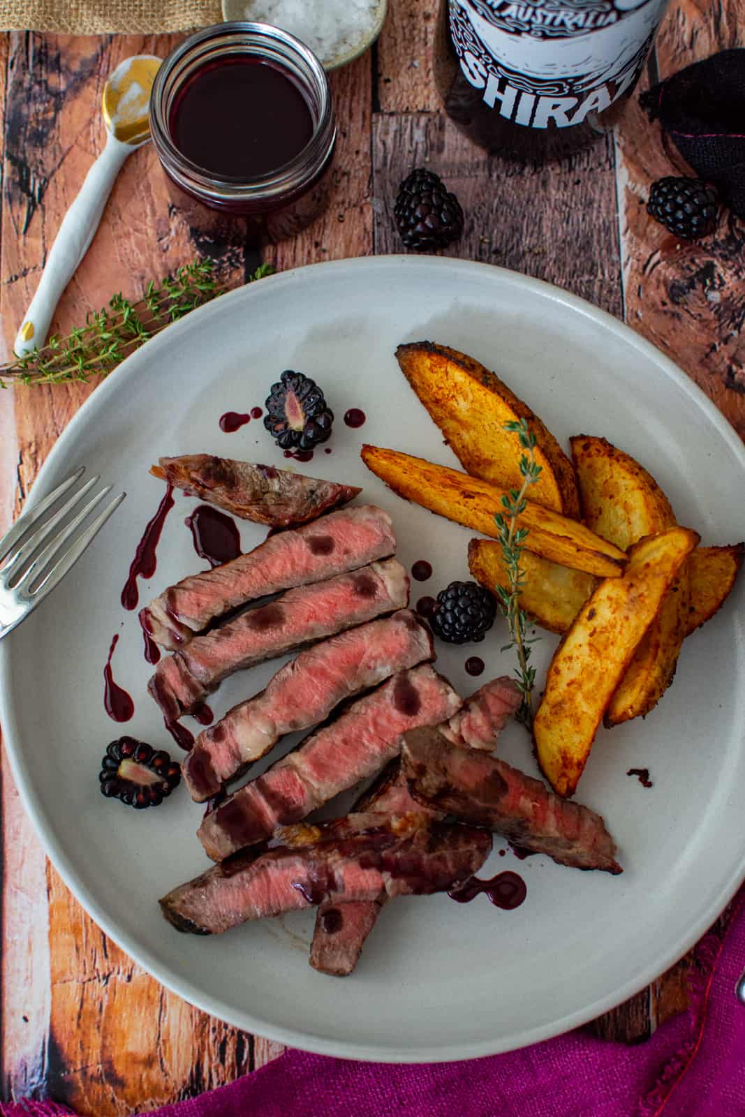 grilled scotch fillet on a plate with spicy wedges and blackberry jus