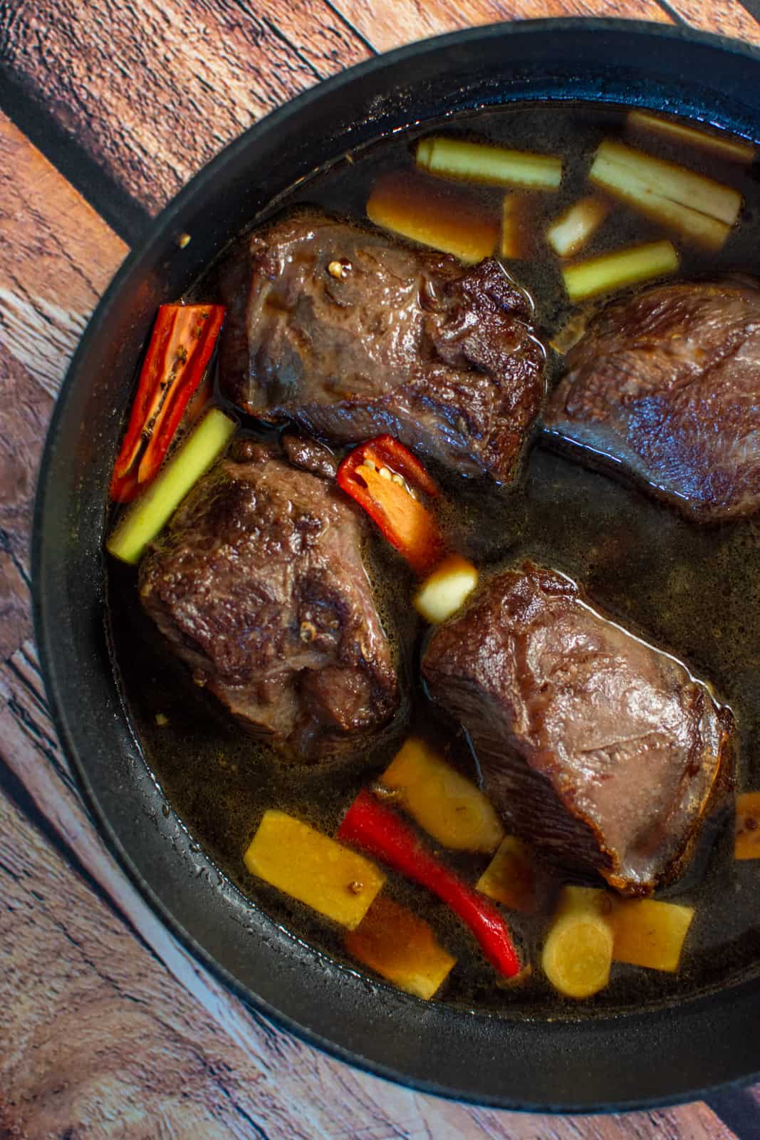 seared beef cheeks and asian ingredients in a saucepan ready to be cooked