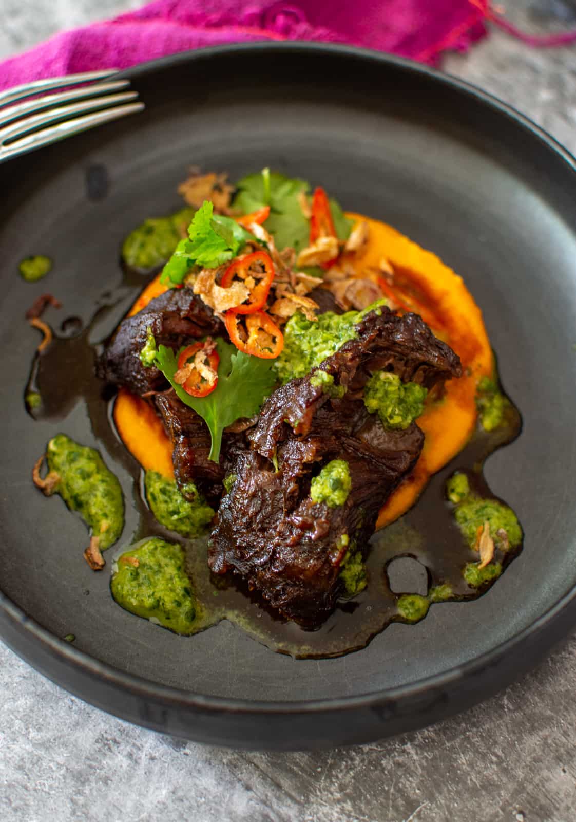 asian slow cooked beef cheeks in a black bowl with nam prik dressing