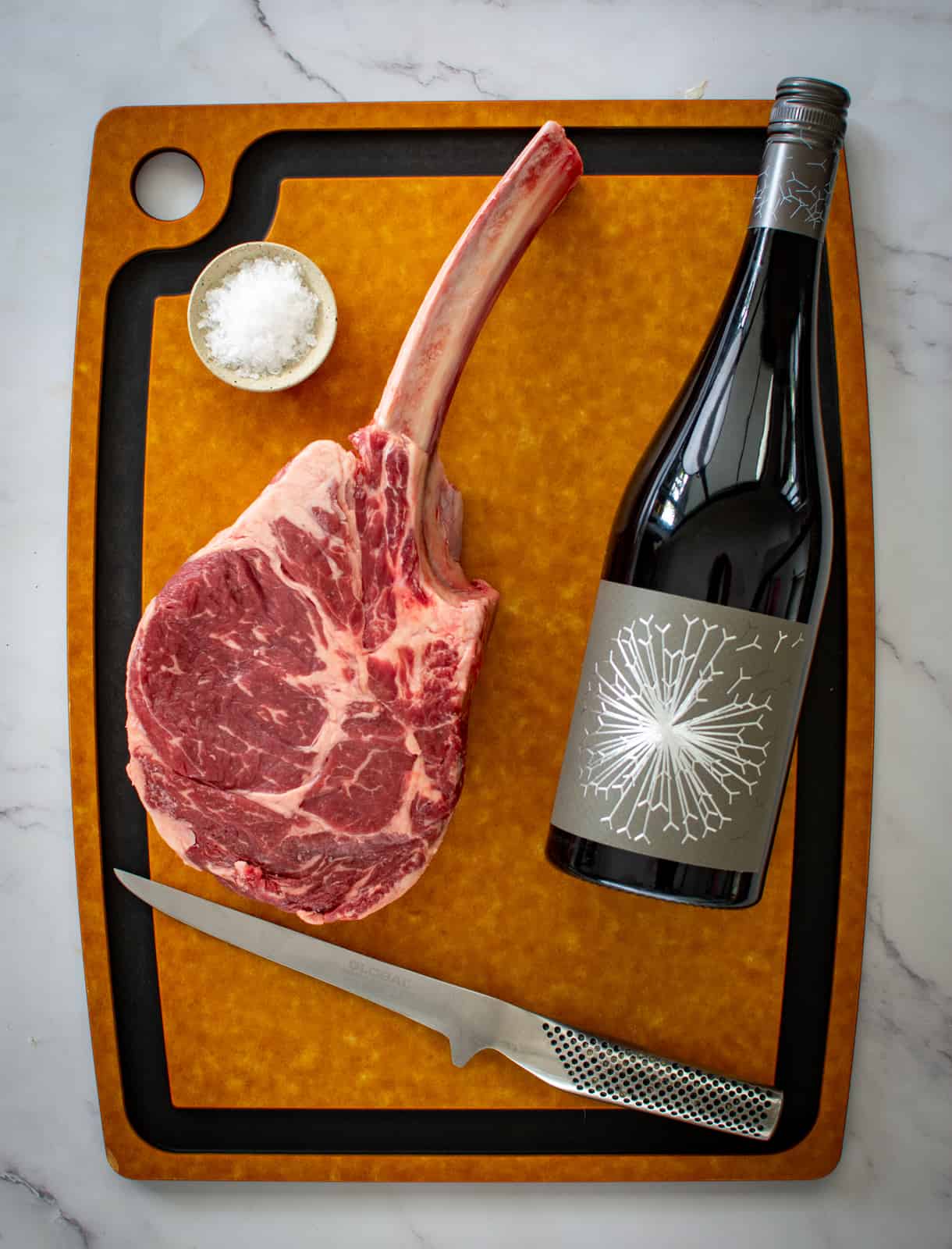 tomahawk steak and a bottle of wine on a chopping board