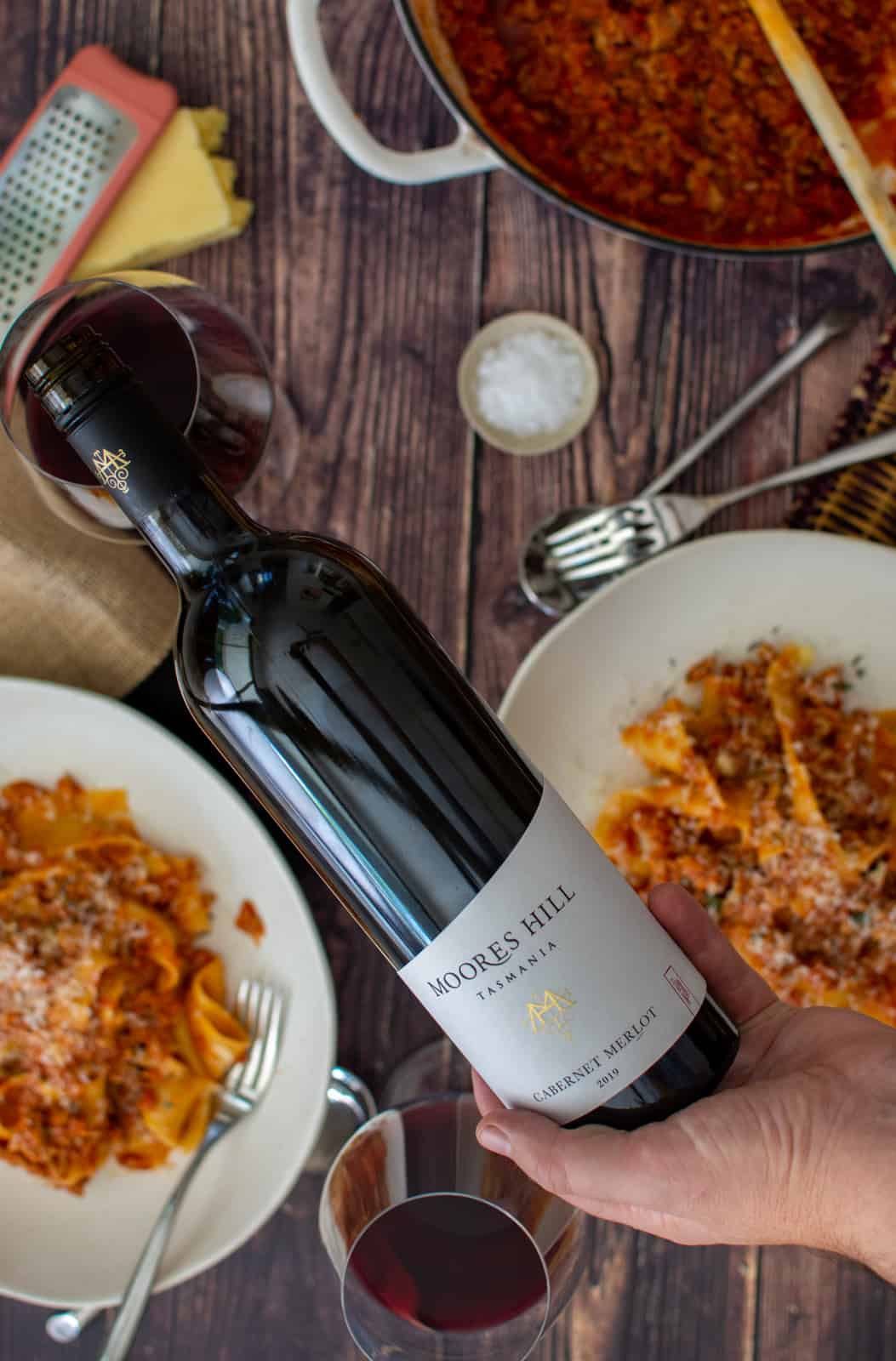 someone pouring Moores Hill wine with food on a table below