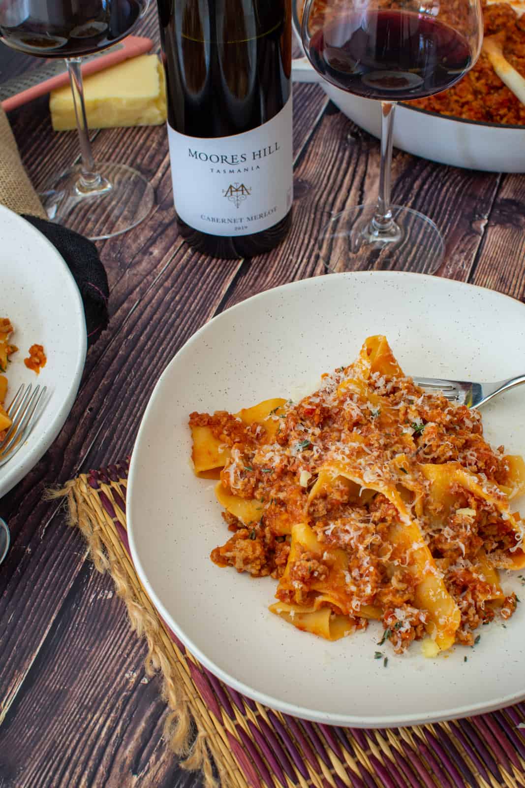 a bowl of pork chorizo ragu, moores hill red wine and casserole dish on a wooden table