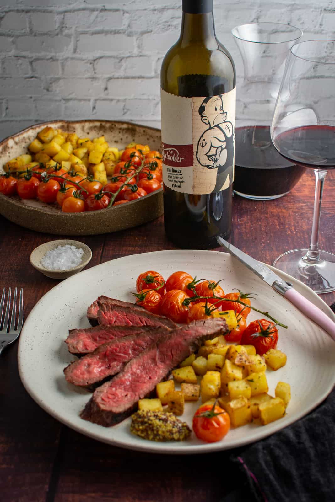 bavette steak, potatoes & tomatoes on a plate. Mollydooker red wine and wine glass in background