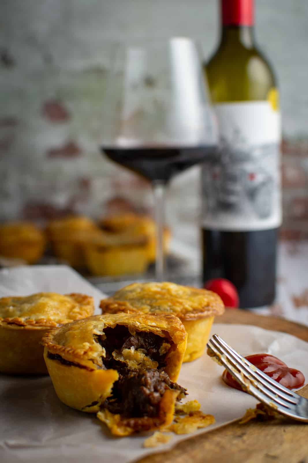close up of chunky beef pie with a fork & ketchup beside it