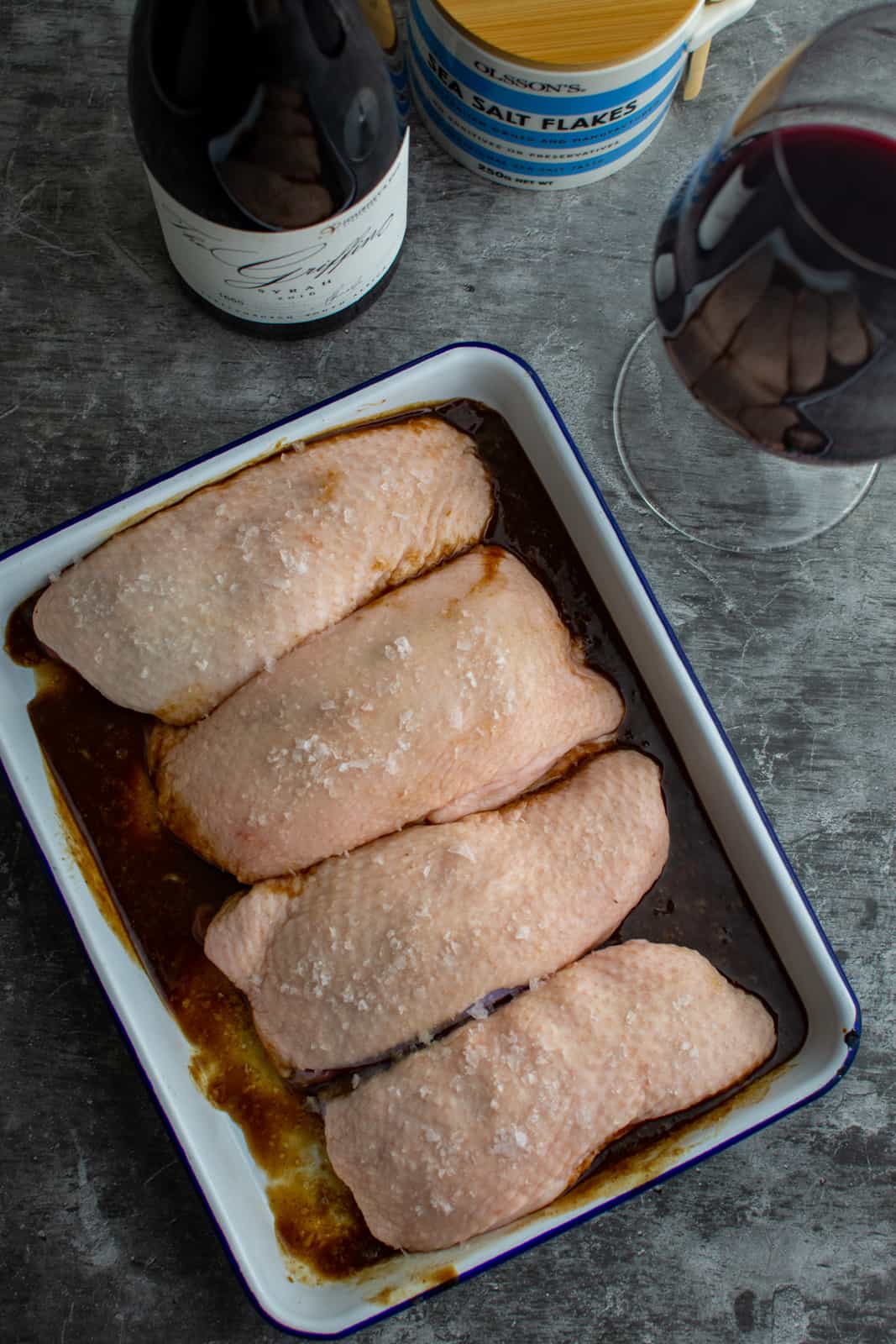 duck breast marinating, red wine and salt next to them 