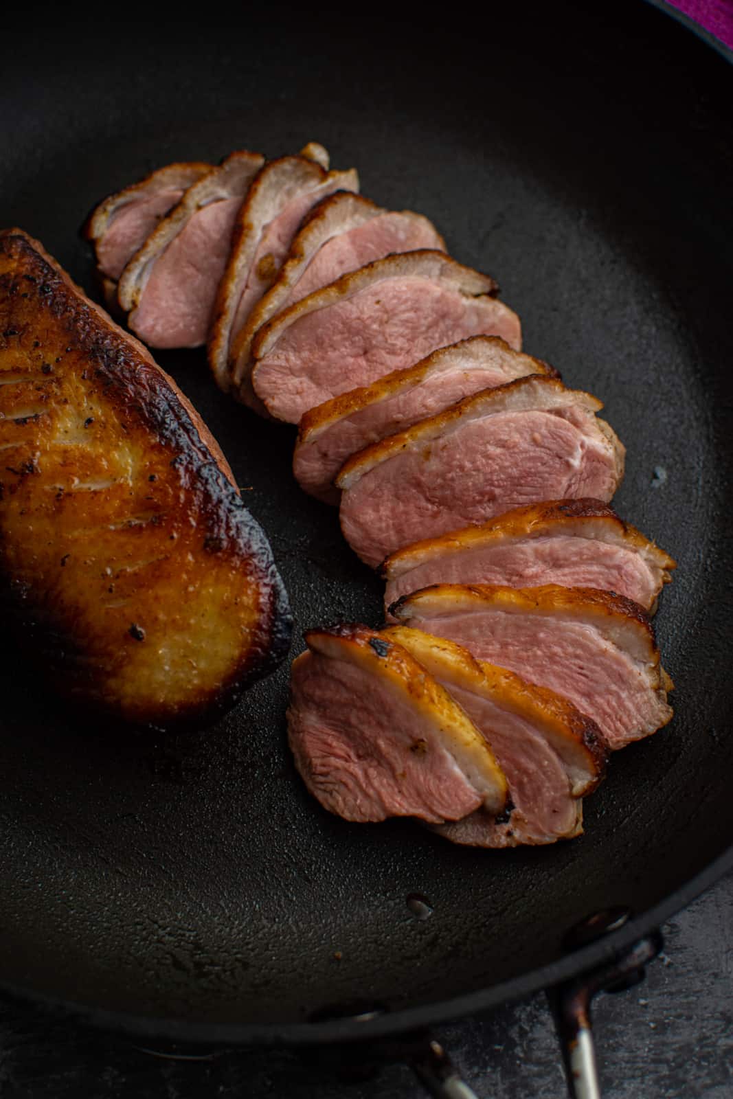 cooked and sliced peking duck breast in frying pan 